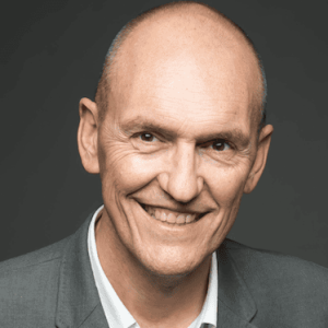 Homme souriant en costume gris, portrait professionnel pour Elixir Conseil.